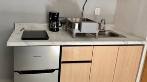 Una cucina compatta con un frigorifero Hisense, una macchina per il caffè, un lavandino e un piano di lavoro.