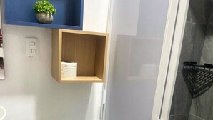 A bathroom with a toilet, a small shelf with a plant, a shower area, and a sink. - Smart loft with convertible bed/desk in Alameda (Santiago de Querétaro)
