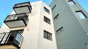 A modern multi-story building with balconies and a large garage door. - Smart loft with convertible bed/desk in Alameda (Santiago de Querétaro)