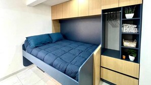 A modern bedroom with a bed, built-in wardrobe, and shelves. - Smart loft with convertible bed/desk in Alameda (Santiago de Querétaro)
