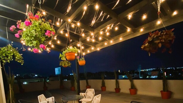 An outdoor patio with hanging plants, string lights, and seating. - Smart loft with convertible bed/desk in Alameda (Santiago de Querétaro)
