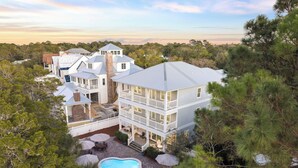 A large, multi-story house with a swimming pool, surrounded by trees. - Walk to Seaside, Beach! Private Pool & LSV! Sleeps 24, PETS OK! (Santa Rosa Beach)