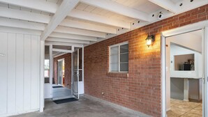 A hallway with a brick wall, a glass door, and a white ceiling. - Central Tucson Gem w/ Porch, Patio & Park Access (Tucson)