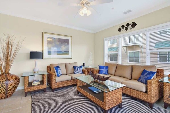 A living room with a sofa set, a glass coffee table, a decorative vase, and a framed picture on the wall. - Rising Tide by Brunswick Vacation Rentals: 4BR w/ Deck & Views, Near the Ocean! (Ocean Isle Beach)