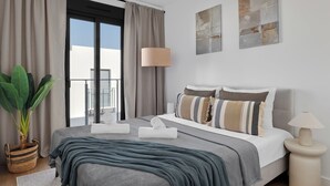 Ein modernes Schlafzimmer mit einem großen Bett, einer Topfpflanze und Blick ins Freie.