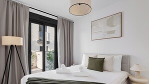 Ein modernes Hotelzimmer mit einem großen Bett, einem Nachttisch, einer Lampe und Blick ins Freie.