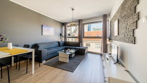 A modern living room with a sofa, coffee table, and dining area.