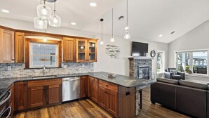 A modern kitchen with wooden cabinets, a built-in dishwasher, and a stone backsplash. - Mott's Lakefront Landing: Dog-Friendly Lakefront Escape on Seneca Lake! (Lodi)