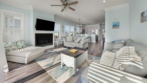 A spacious living room with a fireplace, sofas, a coffee table, and a ceiling fan. - Sandy Bottoms by Carolina Getaway: Elevator Home w/ Ocean Views & Steps to Beach (Surf City)