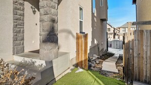 En bostadsfastighet med en fasad av sten, en trälucka och en välskött gräsmatta.