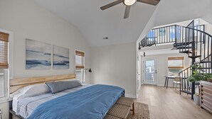 Un dormitorio con cama, ventilador de techo y una escalera que conduce a un nivel superior.