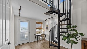 Een modern interieur met een trap, een eethoek en een potplant.