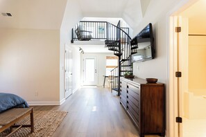 Ein geräumiger Flur mit Treppe, Essbereich und einer Küche inklusive Fernseher.