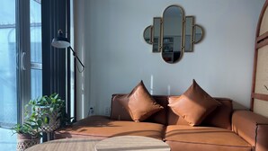 Ein modernes Wohnzimmer mit einem Ledersofa, zwei runden Holztischen und einem wandmontierten Spiegel.