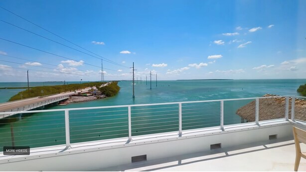 Vista costera con un puente, cielo despejado y aguas tranquilas.