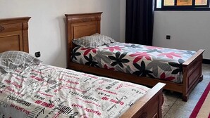Un dormitorio con dos camas de madera, una ventana con cortinas y una alfombra roja.