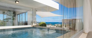 Ein moderner Infinity-Pool mit klarem, blauem Wasser, großen Fenstern und Blick auf den Ozean.