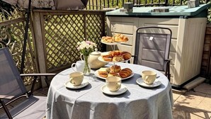 A round table with a tablecloth, surrounded by chairs, and a tiered stand with pastries and cups.
