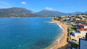 Une ville côtière avec une plage, des bâtiments et des montagnes en arrière-plan.