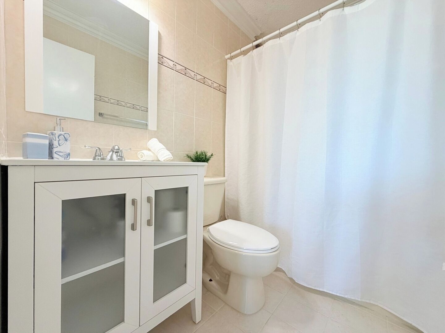 Ein Badezimmer mit weißem Waschtisch, Toilette und Duschvorhang.