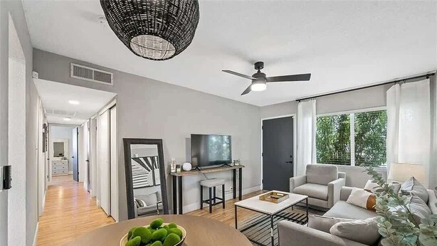 Una sala de estar moderna con televisor, zona de estar y una mesa de comedor con un tazón de elementos verdes.