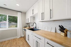 Eine moderne Küche mit weißen Schränken, einer schwarzen Spüle und einer Holz Arbeitsplatte.