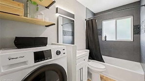Un baño pequeño con lavadora, inodoro y zona de ducha.