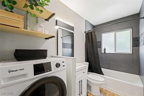 Ein kleines Badezimmer mit Waschmaschine, Toilette und Duschbereich.