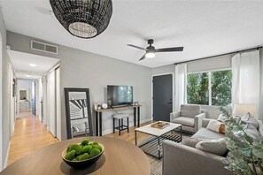 Una sala de estar moderna con televisor, sofá y comedor.