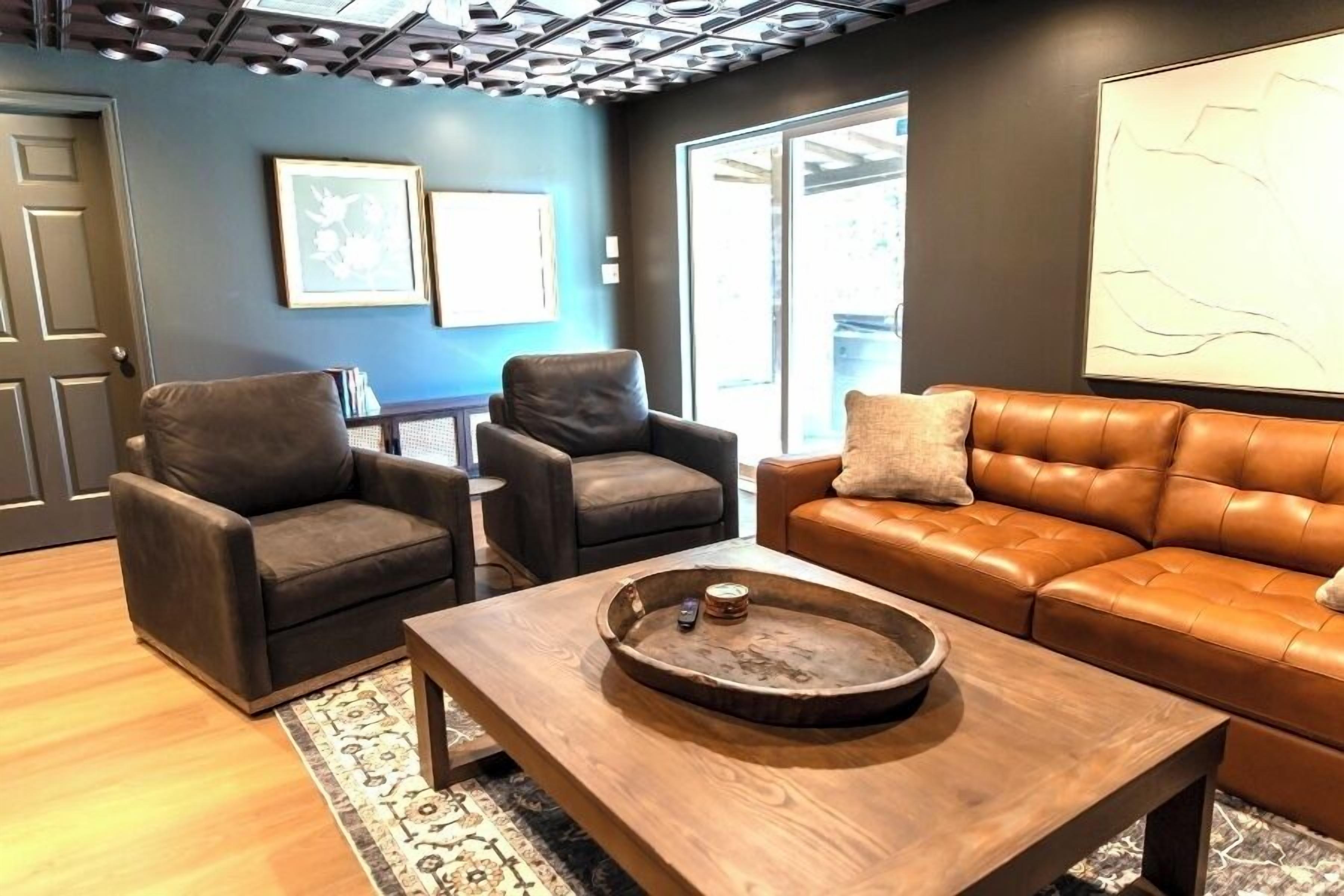 Un moderno salón con sofás de cuero, una mesa de centro de madera y una alfombra estampada.