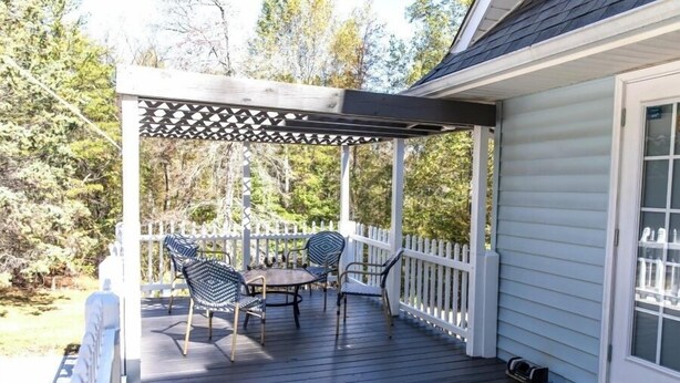 Katettu ulkoterassi, jossa on pergola, pöytä ja neljä tuolia.