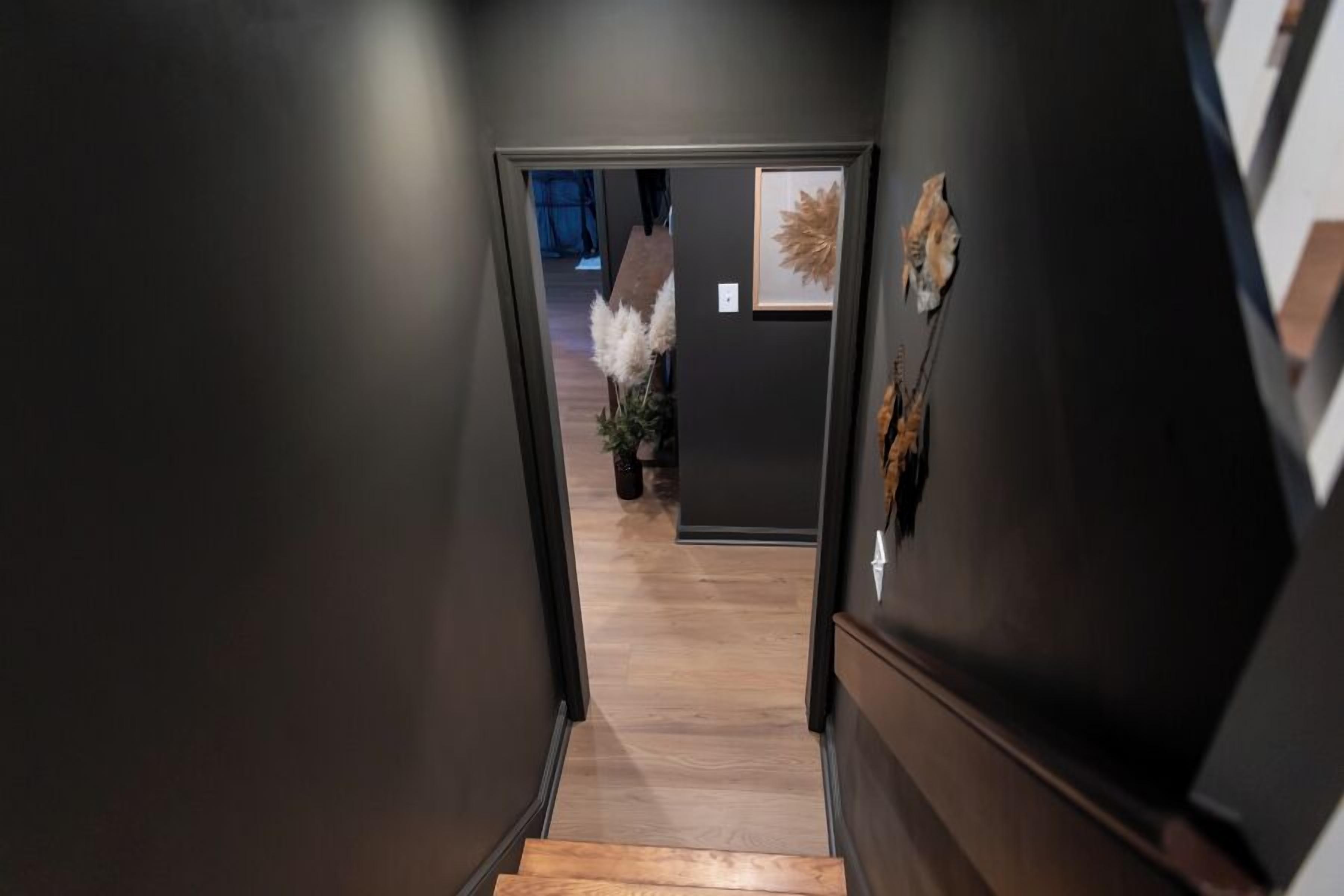 A narrow hallway with a wooden staircase leading to a room.