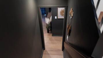 A narrow hallway with a wooden staircase leading to a room.