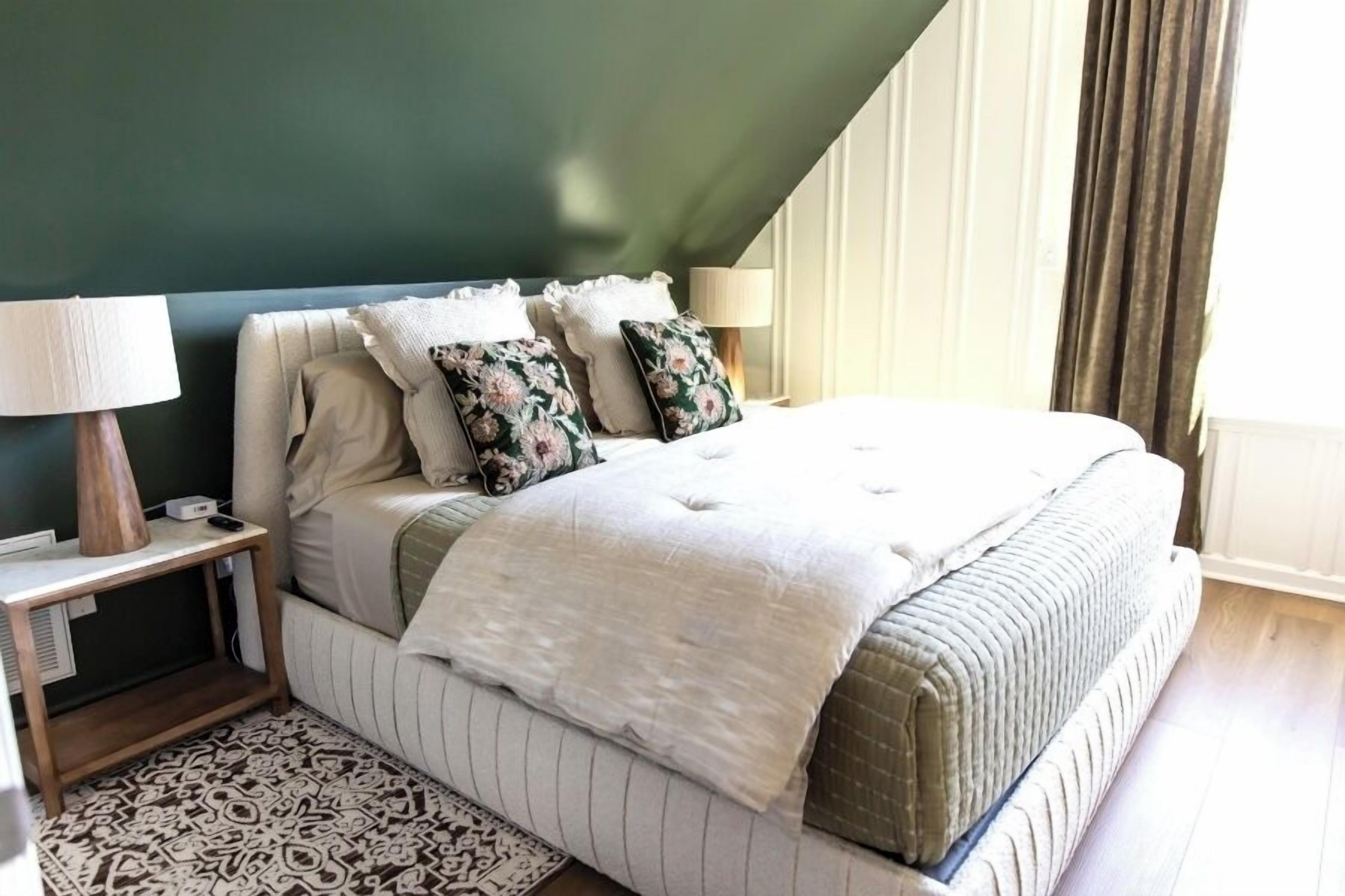 Un dormitorio ordenado con cama, mesitas de noche y un tapete estampado.