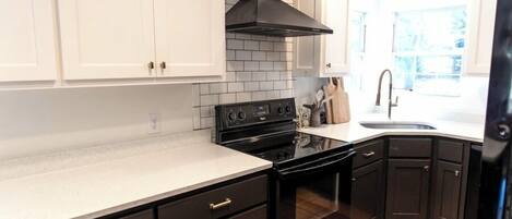 A modern kitchen with white cabinets, a black stove, and a black range hood.