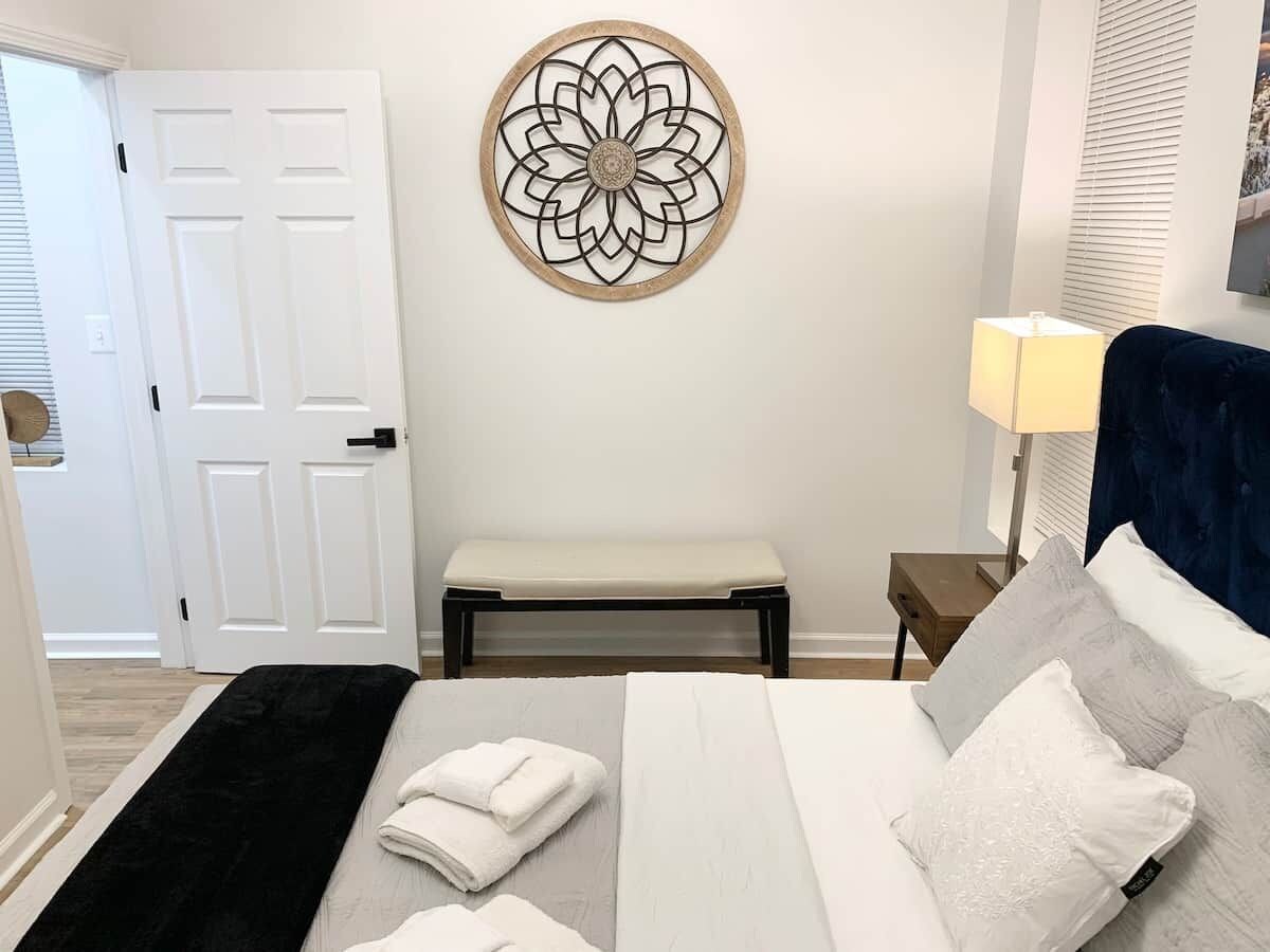 A bedroom with a bed, a bench, a bedside table, and a wall decoration.