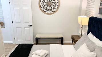 A bedroom with a bed, a bench, a bedside table, and a wall decoration.