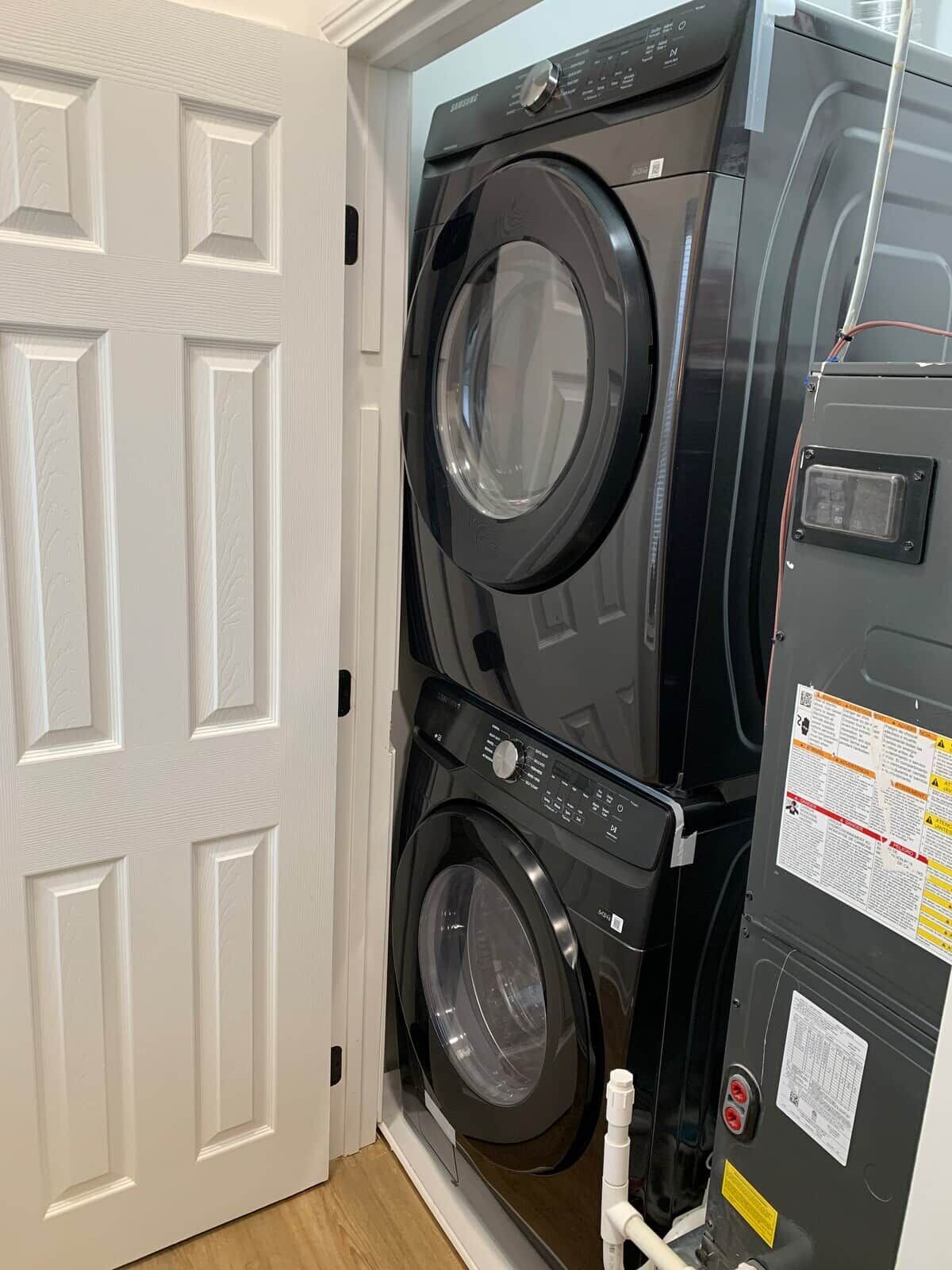 A stacked washer and dryer unit in a room with white doors.