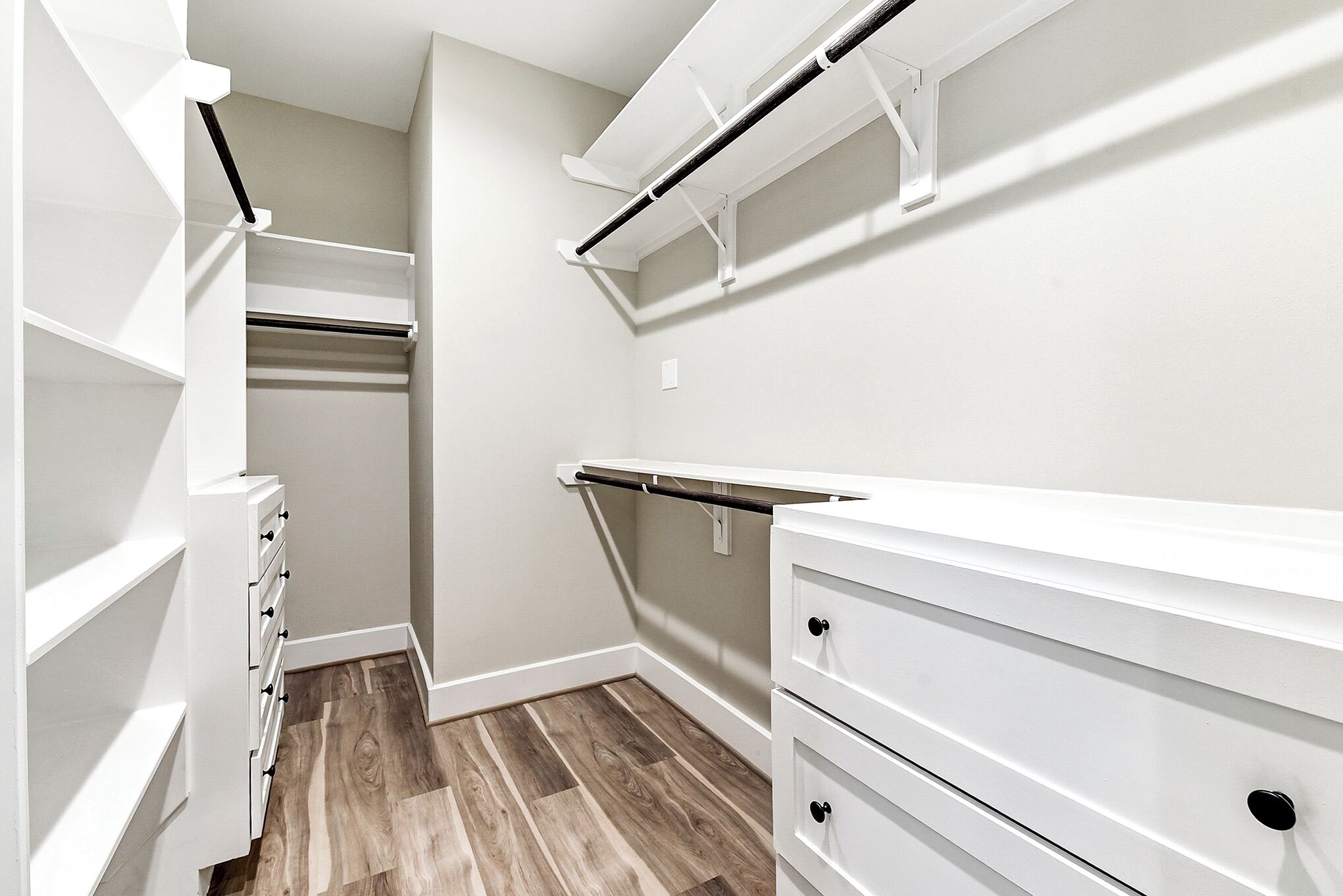 Un dressing accessible sans porte, avec des étagères blanches, un radiateur intégré et un plancher en bois.