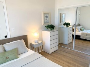 A bedroom with a bed, bedside table, dresser, and a mirror. - Comfy Cozy 2BD/1.5BA apt in Federal Hill (Baltimore)