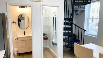 A modern apartment with a bathroom, a dining area, and a staircase.