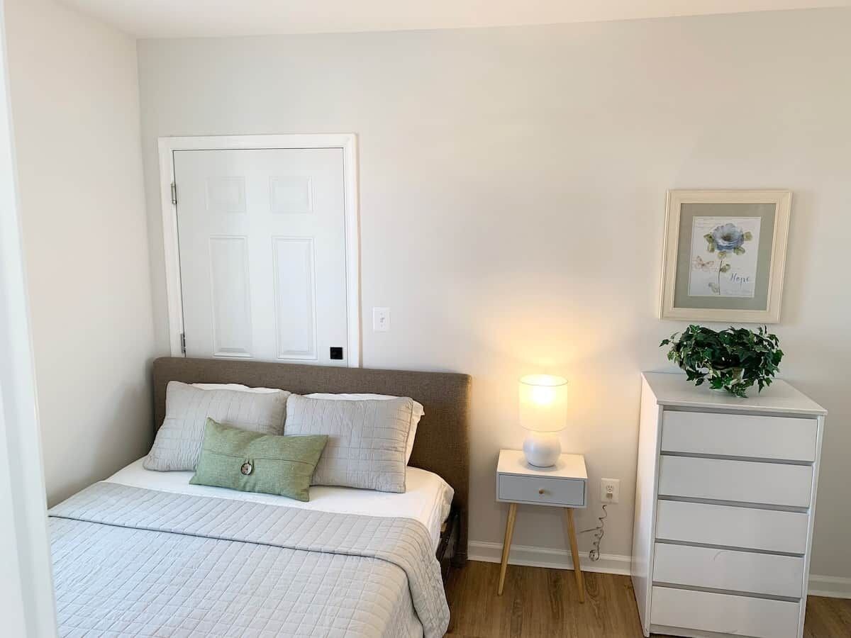 Ein Schlafzimmer mit Bett, Nachttisch, Lampe und Kommode.