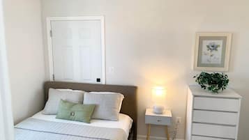 Ein Schlafzimmer mit Bett, Nachttisch, Lampe und Kommode.