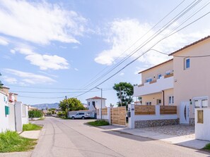 A residential street with houses, a white car parked on the side, and a mountain in the background. - 2 bedroom apartment, plot with pool (Empuriabrava)
