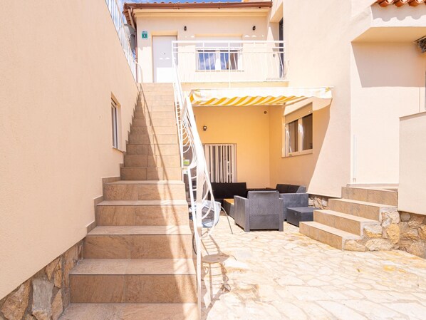 A stone staircase leading to a covered outdoor seating area with wicker furniture. - 2 bedroom apartment, plot with pool (Empuriabrava)