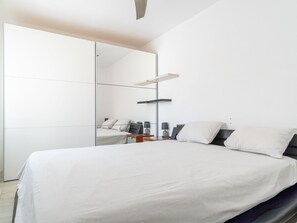A modern bedroom with a large bed, a mirror, and a desk with a chair. - 2 bedroom apartment, plot with pool (Empuriabrava)