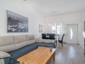 A modern living room with a sofa, a wooden coffee table, and a dining area with chairs and a table. - 2 bedroom apartment, plot with pool (Empuriabrava)