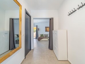 A hallway leading to a bedroom with a bed, a wardrobe, and a large mirror. - 3 bedroom apartment, plot with pool (Empuriabrava)