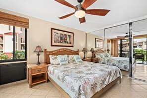 A hotel room with a large bed, two nightstands, a ceiling fan, and a large window with a view of the outside. - Beach, Pool & Pickleball Short Walk to Beach! (Kihei)