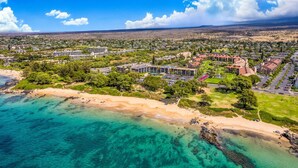 An aerial view of a coastal resort with beachfront properties, dense greenery, and a clear blue sky. - Beach, Pool & Pickleball Short Walk to Beach! (Kihei)